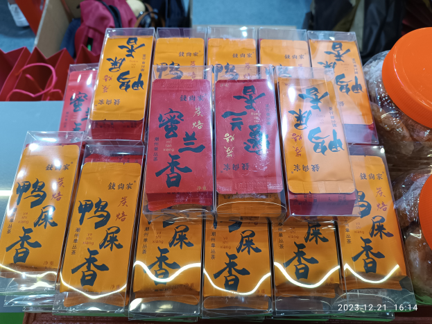 Ein Tisch voller verschiedener Lebensmittel, darunter Packungen, Schachteln und Taschen, mit einer Person im Hintergrund bei einer Feier zum chinesischen Neujahr.