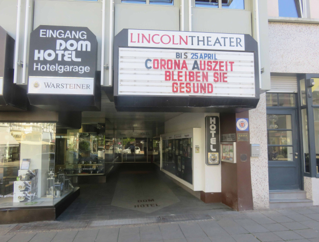 Außenansicht des Lincoln Theaters in Berlin, Deutschland, mit Glasfenstern und -türen, sowie einer Schautafel und einem belebten Innenraum.