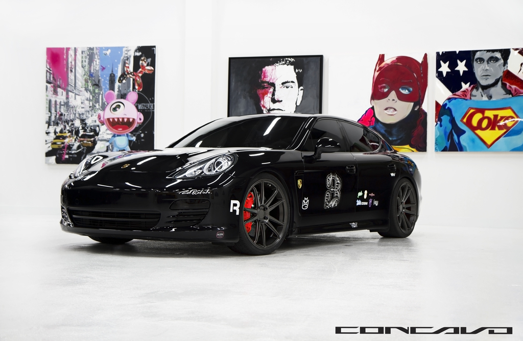 Ein schwarzer Nissan-Sportwagen mit Cartoon-Plakaten im Hintergrund und einem kleinen Zitat unten.