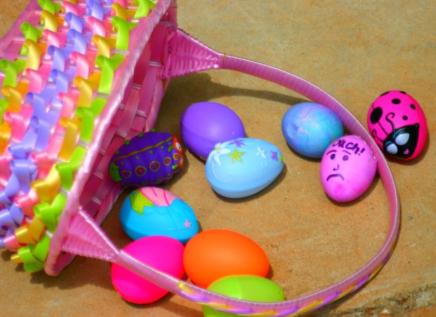 Ein geflochtener Korb mit mehreren bunten Ostereiern, der an einer Wand lehnt.