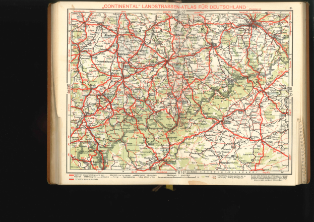 Offenes Buch mit einer detaillierten Karte von Deutschlands Straßen und Autobahnen auf schwarzem Hintergrund.