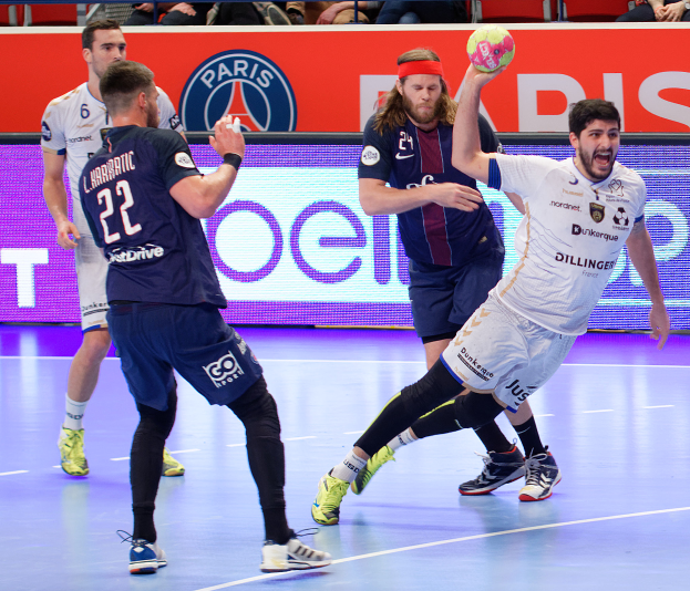 Eine Gruppe von Männern, die Handball auf einem Court spielen, mit einem Ball in der Mitte der Aktion und Zuschauern im Hintergrund mit einer Fahne, auf der "Futsal World Cup 2019 - Paris Saint-Germain vs Marseille" steht.