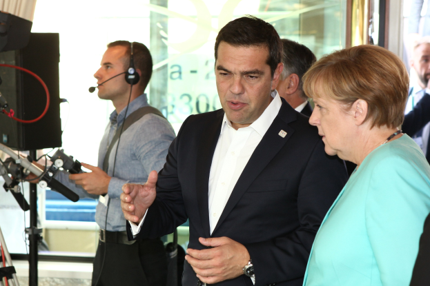 Bundeskanzlerin Angela Merkel und Bundeskanzler Joachim Gauck in Anzügen, die vor einer Glaswand mit einem Vorhang sprechen.