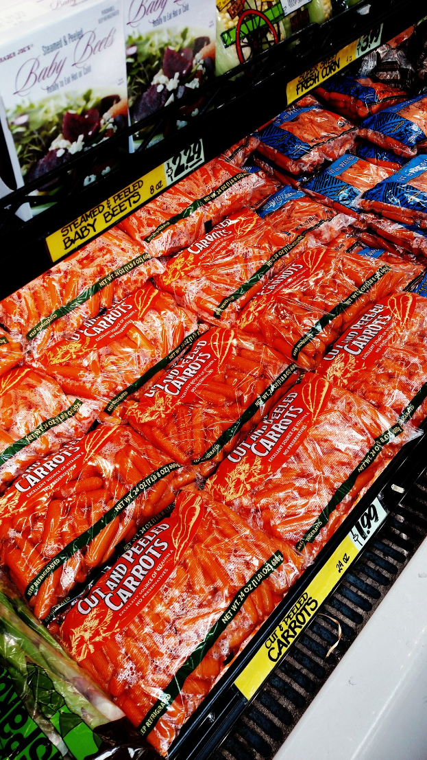 Geschäftsregal mit Packungen von Gemüse und angehängten Preisschildern.