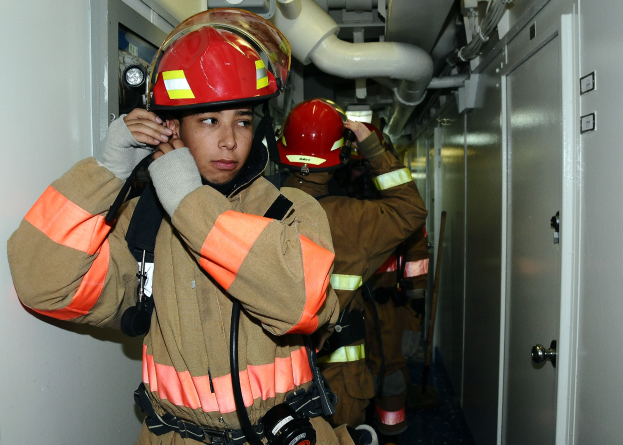 Feuerwehrleute in Uniform, die in einem Raum mit Rohren und Ausrüstung während eines Trainingsübung stehen.