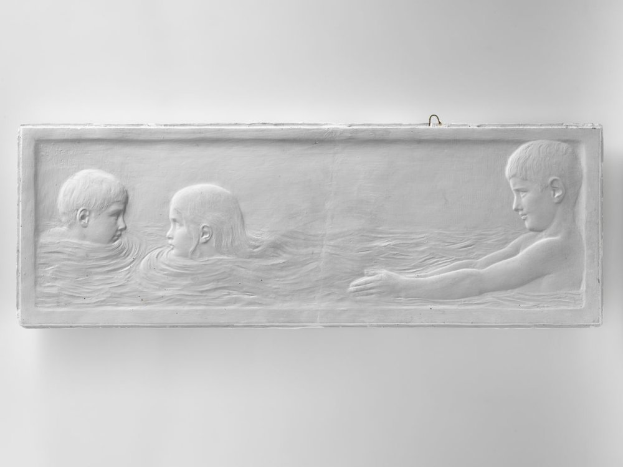 Drei Kinder beim Schwimmen in Wasser, mit einer Wand im Hintergrund, dargestellt in einem Schwarz-Weiß-Foto.