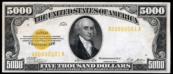 Ein US-amerikanischer Fünftausend-Dollar-Schein mit einem Porträt von George Washington, auf dem 'United States' und 'Fünftausend Dollar' in fetter Schrift auf einem schwarzen Hintergrund stehen.