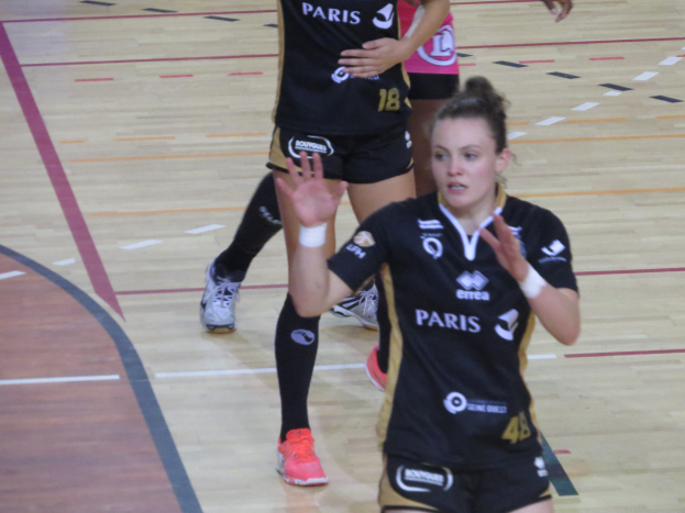 Eine Gruppe von Frauen in Sportkleidung und -schuhen beim Volleyballspielen auf einem Platz.