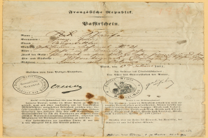 Ein altes, gelbliches Dokument mit einem kreisförmigen, schwarz umrandeten Stempel, das schwarze Tintenzeichen enthält, wahrscheinlich ein Brief der deutschen Regierung.