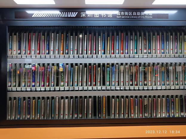 Eine gut beleuchtete Bibliothek mit Reihen von Bücherregalen, einer Texttafel und einem Stadtblocks-Wasserzeichen unten.