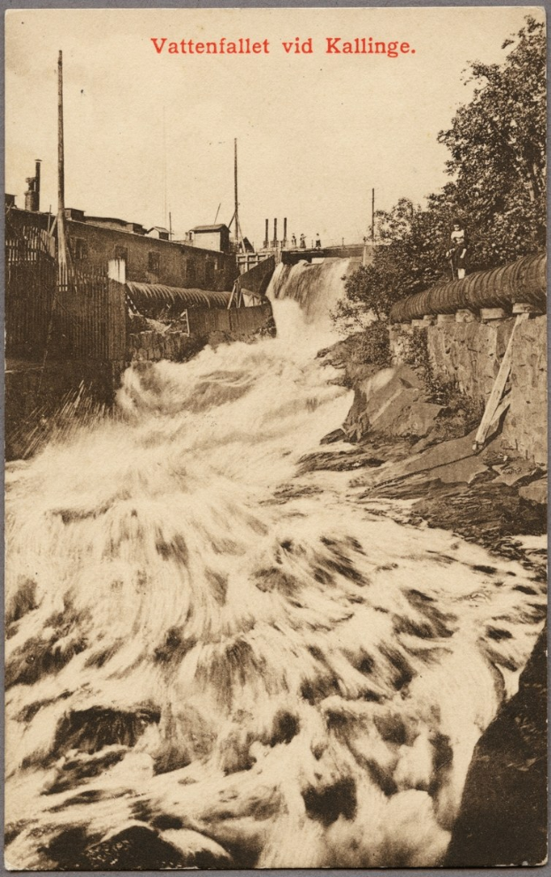 Altes Foto eines Flusses unter einer Brücke mit Bäumen, Gebäuden, Strommasten und einem Zaun am Ufer und Text oben.