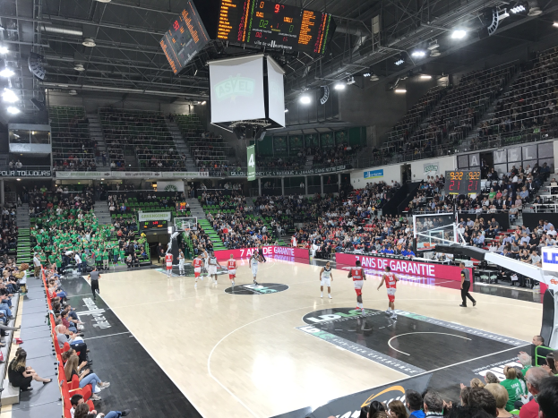 Basketballspiel in einer großen Arena mit Zuschauern, mit den Mannschaften Asvel und Galatasaray, wie auf dem Scoreboard-Text zu sehen ist.