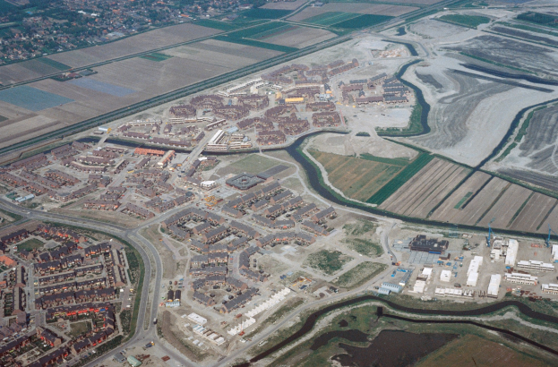 Luftaufnahme einer Stadt mit dichtem Baumbestand, Straßen, Grünflächen, Bäumen und einem zentralen Reservoir, das von städtischen Gebieten umgeben ist.