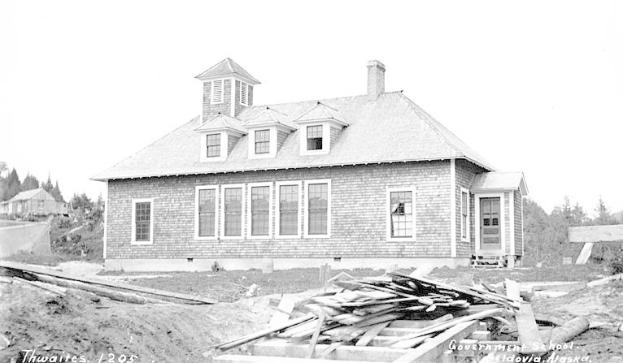 Schwarzes und weißes Foto eines Regierungsgebäudes aus dem Jahr 1905 mit Fenstern, Türen, umgeben von Bäumen unter einem klaren Himmel und hölzernen Brettern unten mit der Aufschrift "Regierungsgebäude, Thwaites, 1905".