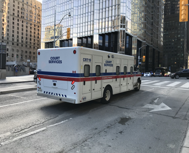 Ambulanz auf einer Stadtstra├če mit hohen Geb├Ąuden, Stra├čeninfrastruktur und Passanten im Hintergrund.