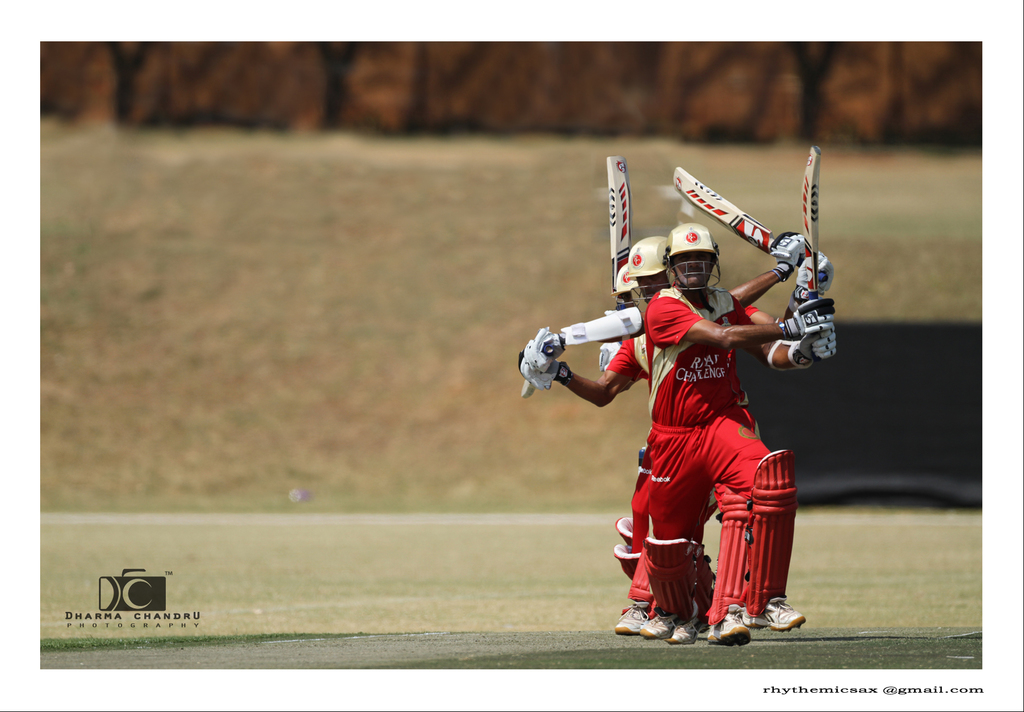 Eine Gruppe von Spielern, die auf einem Feld stehen, alle die gleiche Uniform tragen und Schläger halten, mit einer Wand im Hintergrund und einem Wasserzeichen in der unteren linken Ecke.