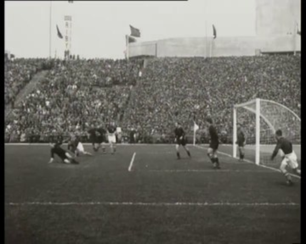 Schwarzes und weißes Foto des WM-Finales 1958 zwischen Manchester United und Liverpool in einem Stadion, das Spieler auf dem Feld, ein Tor auf der rechten Seite, Zuschauer in den Rängen und Fahnen mit Stangen gegen einen klaren Himmel zeigt, mit dem Text "1958-1958 WM-Final - Manchester United v Liverpool" oben und unten.
