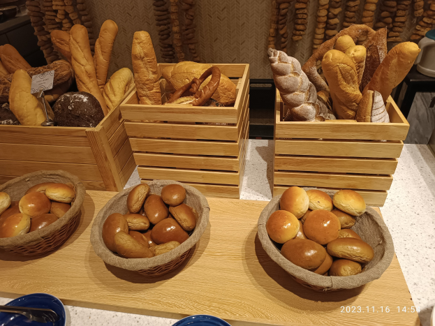 Holztisch mit Körben voller Brote, Tellern und Löffeln in einer Pariser Bäckerei.