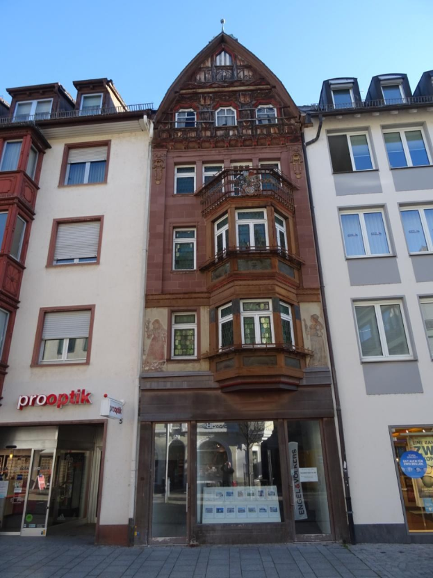 Gewerbliches Immobiliengebäude zum Verkauf in Heidelberg, Deutschland, mit mehreren Fenstern an der Seite, das sich neben einer Straße mit einem klaren blauen Himmel befindet.