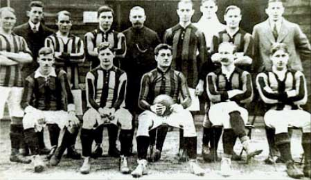 Ein Schwarz-Weiß-Foto einer Fussballmannschaft, einige stehen, einige sitzen, vor einer Wand, mit dem Text "Ballymena Football Club" unten.