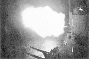 Ein Schwarz-Weiß-Foto einer großen Explosion in einem dunklen Raum, mit Rauch, der herausquillt, einem Pfahl und einer Wand rechts und Text unten.