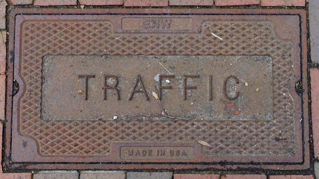 Ziegelweg mit einem Metall-Schachdeckel beschriftet mit "Verkehr."