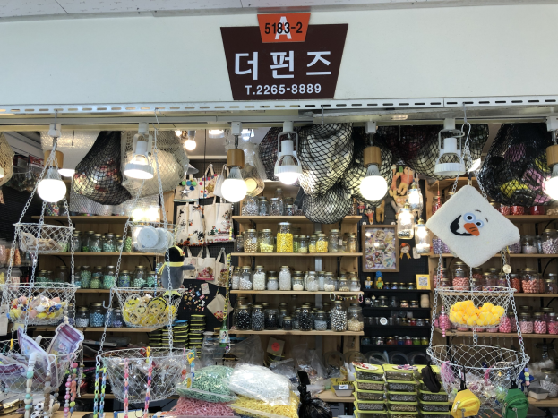 Ein Geschäft mit verschiedenen Artikeln wie Körben, Lampen, Flaschen und Spielzeugen auf Regalen, mit einem Schild oben, das es als bestes koreanisches Geschäft in Seoul ausweist.
