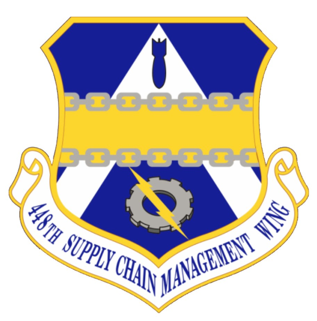 Logo der 48. Supply Chain Management Wing mit einem blauen Schild, einem weißen Stern, einem weißen Banner mit der blauen Aufschrift "Supply Chain Management" und schwarzer Schrift "48. Supply Chain Management Wing" in fetter Schrift.