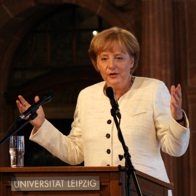 Bundeskanzlerin Angela Merkel hält eine Rede an einem Pult mit einem Mikrofon und einem Glas Wasser an der Universität Leipzig.