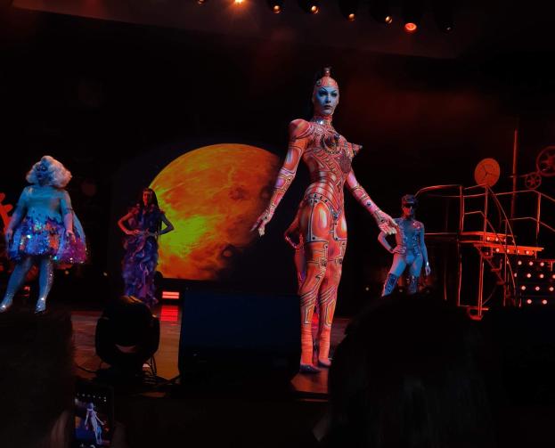 Eine Frau in Kostüm performs auf einer hell erleuchteten Bühne bei der Eröffnungsnacht einer Cirque du Soleil Show in Paris, mit einem Publikum unten und einem Bildschirm oben.