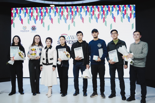 Eine Gruppe von Menschen auf einer Bühne mit Bücher und Blumensträußen, im Hintergrund ein Bildschirm mit der Aufschrift "Yogyakarta International School of Science and Technology."