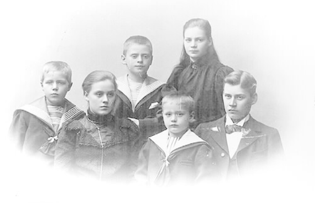 Schwarzes und weißes Foto einer Familie, die mit einem jungen Jungen in der Mitte posiert, umgeben von seinen Geschwistern.