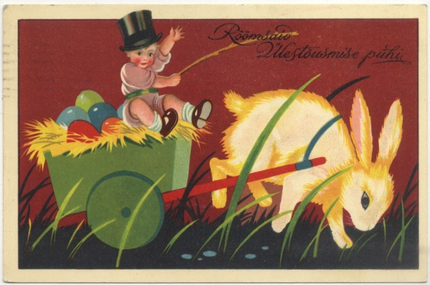 Eine alte Postkarte mit einem Baby in einem Zylinder, das einen Karren voller bunter Ostereier schiebt und von einem Hasen begleitet wird, mit handgeschriebenen Ostergrüßen.